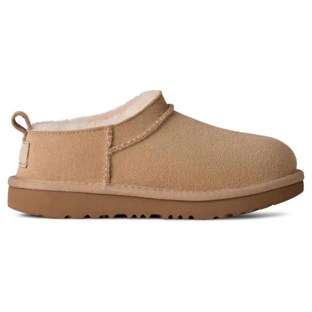 light brown/tan suede super low-cut UGG boot with off-white shearling lining and a suede heel pull loop, light brown foam outsole with a light brown woven heel logo label